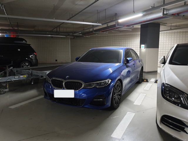 Front three-quarter view of a Portimao Blue 2022 BMW 330i xDrive in a parking garage