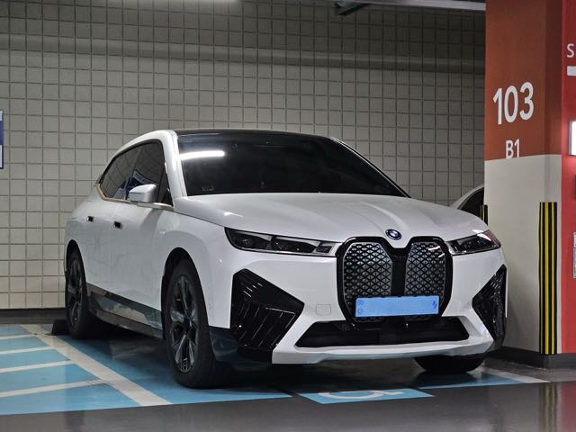 Front three-quarter view of a white 2022 BMW iX xDrive50 in a parking garage